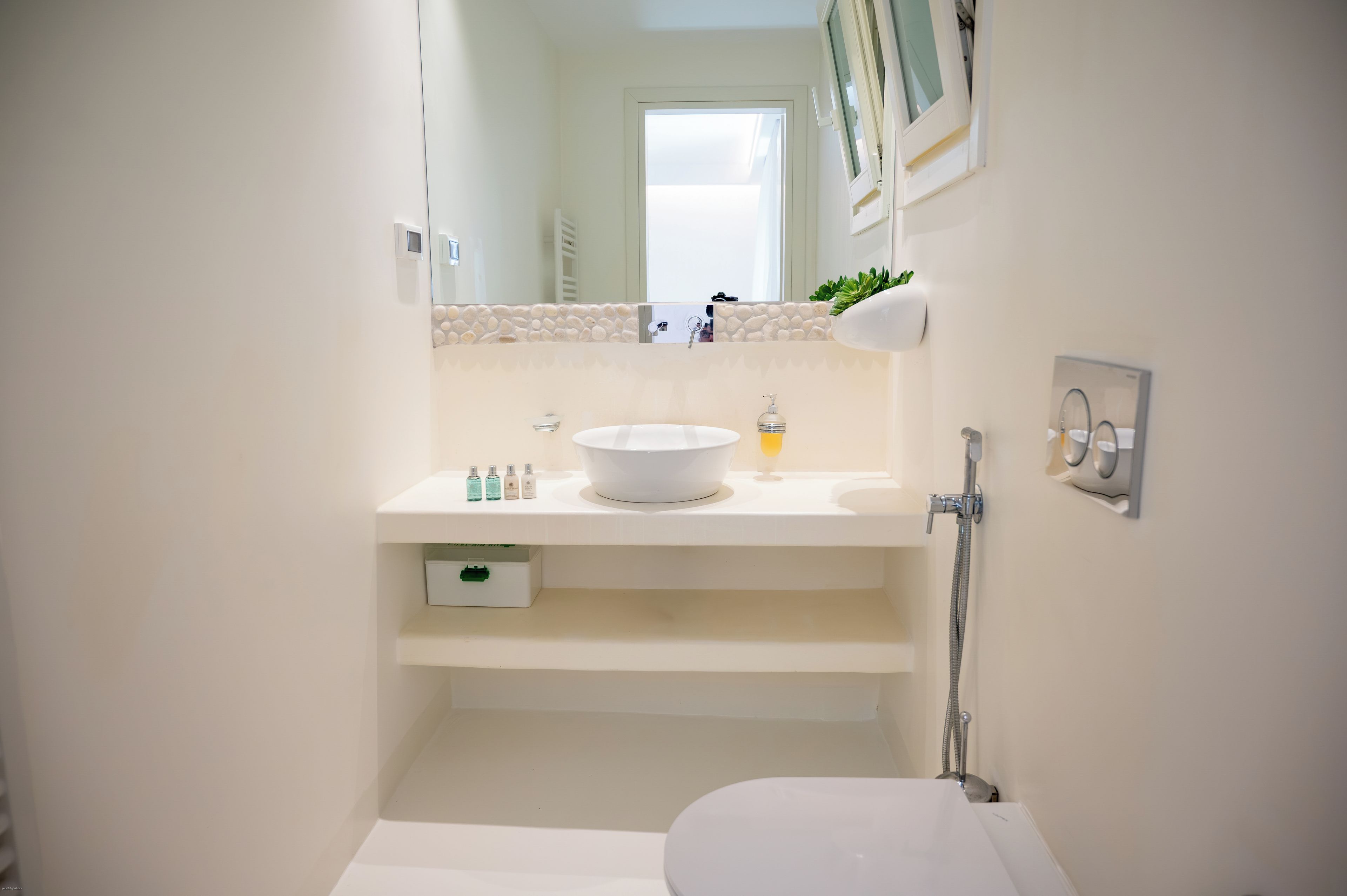 Un baño con lavamanos blanco, espejo, toallero y ducha.