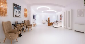 A modern living room with a round coffee table, beige armchairs, a white sofa, and a cactus centerpiece.
