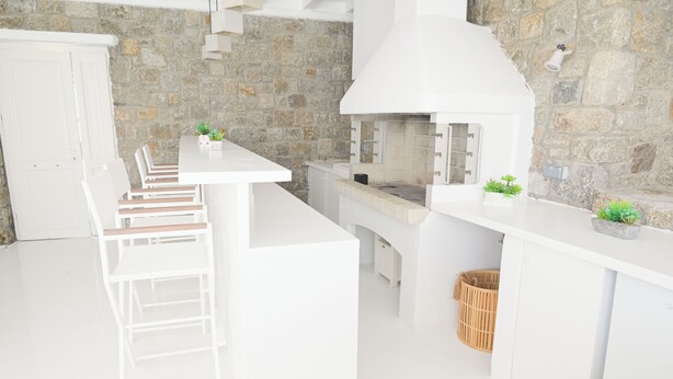 Una cocina moderna con armarios blancos, una pared de piedra y una estufa integrada.