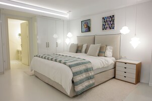 Un dormitorio moderno con una cama grande, mesitas de noche, un armario y un cuadro en la pared.
