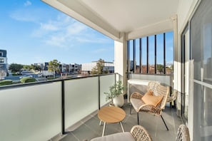 A balcony with a seating area, a potted plant, and a view of the cityscape. - Lakeside Nook | By Host Solutions (Lightsview)