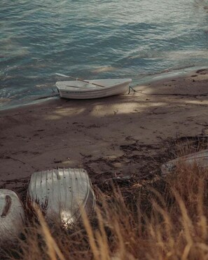 Un bote sobre una playa arenosa con agua de fondo.