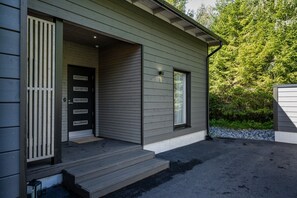A modern house with a grey exterior, a black door with multiple panels, and a small porch with steps leading to the entrance. - Christmas Villa, Private Sauna By Lapland Host (Rovaniemi)