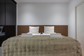 Ein Schlafzimmer mit einem großen Bett, zwei Kissen, einer flauschigen Decke und einem Holzkopfteil.