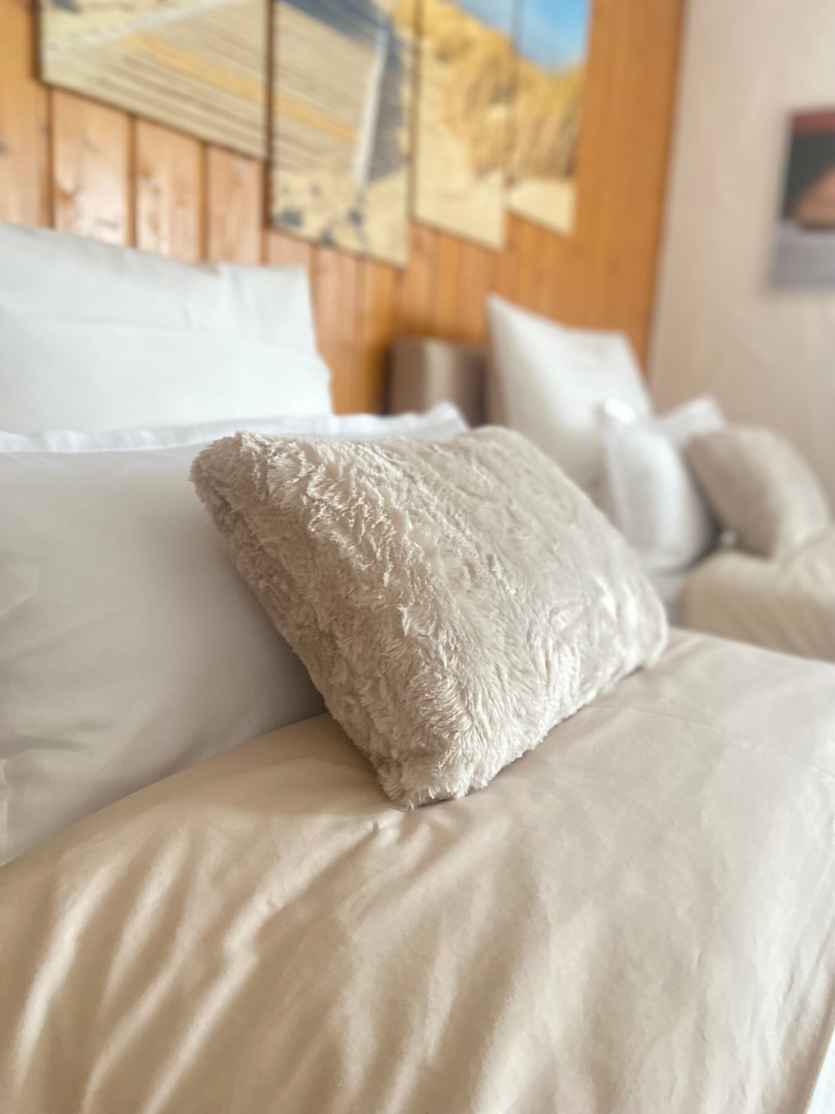 Un lit avec un oreiller moelleux et une tête de lit en bois.
