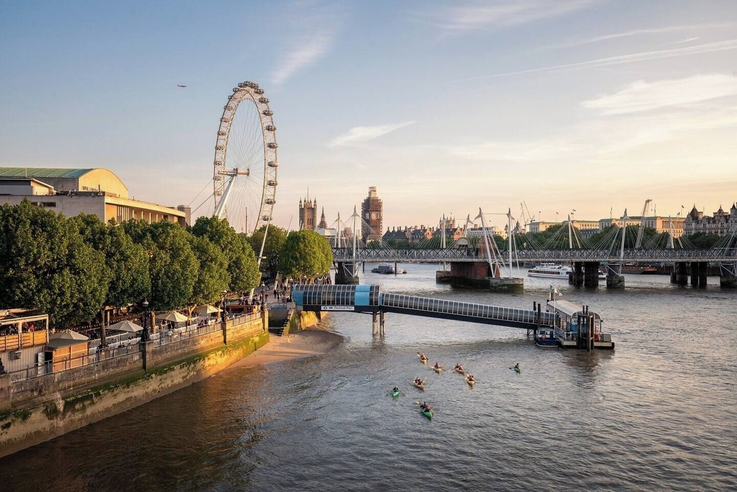 A river with a bridge, a Ferris wheel, and a cityscape in the background.
