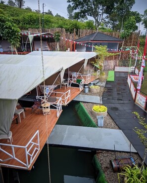 A floating structure with multiple levels, including a dining area with tables and chairs, and a small enclosed space with a table and chairs. - Cozzy Telaga Wangi Riverside (bandung)