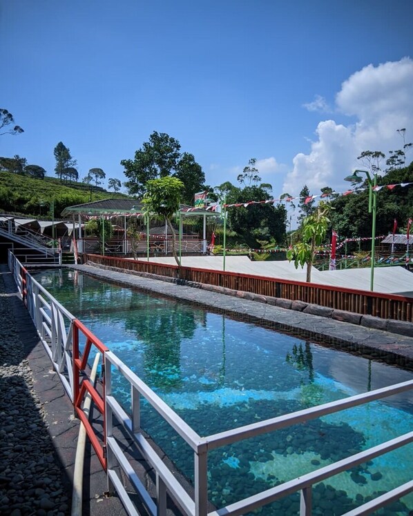 A swimming pool with clear water, surrounded by a wooden deck and metal railings.