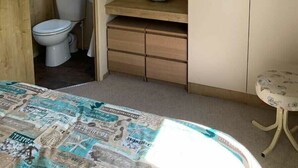 A bedroom with a bed, a bedside table, a wardrobe, a mirror, and a window. - Dinas Cross Country Park - Holiday Accommodation 20053 (Newport)