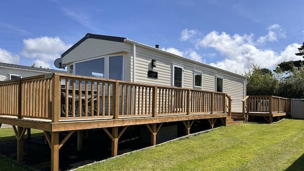 A mobile home with a deck and a fenced yard. - Dinas Cross Country Park - Holiday Accommodation 20053 (Newport)