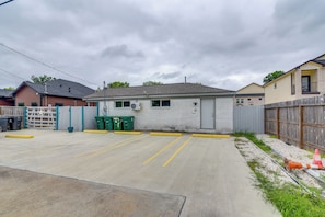 A parking lot with a gated entrance, a building with a grey roof, and a wooden fence. - Dual Houston Homes: 6 Mi to NRG & Med Center (Houston)