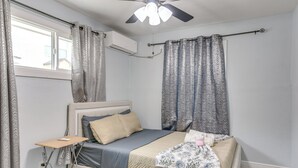 A bedroom with a bed, a bedside table, a ceiling fan, and a window with curtains. - Dual Houston Homes: 6 Mi to NRG & Med Center (Houston)