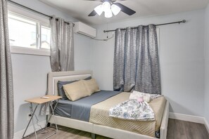 A bedroom with a bed, a bedside table, a ceiling fan, and a window with curtains. - Dual Houston Homes: 6 Mi to NRG & Med Center (Houston)