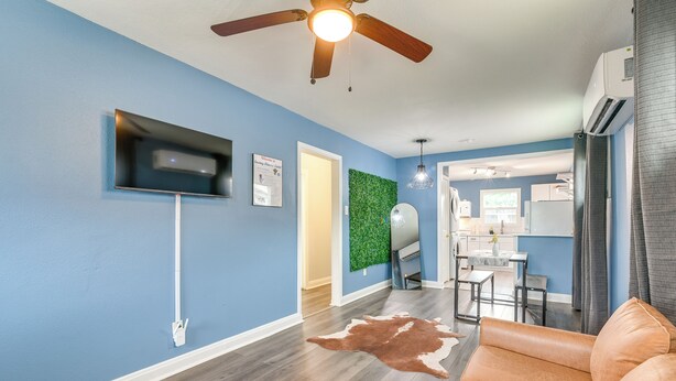 A living room with a ceiling fan, a mounted TV, a cowhide rug, and a sofa. - Dual Houston Homes: 6 Mi to NRG & Med Center (Houston)