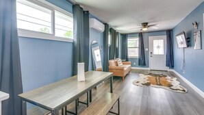 A room with a wooden table, a leather sofa, a ceiling fan, and a cowhide rug. - Houston Group Stay! 2 Homes Near Museum District (Houston)