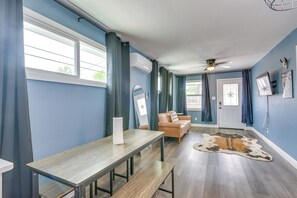 Um quarto com uma mesa de madeira, um sofá de couro, um ventilador de teto e um tapete de couro.