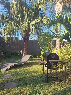 Ein Garten mit Grill, Hängematte und einer Palme.