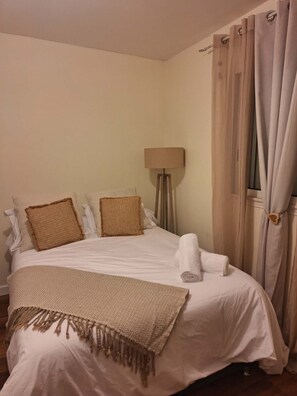 Ein ordentlich bezogenes Bett mit Kissen, einem zusammengerollten Handtuch und einer Decke.