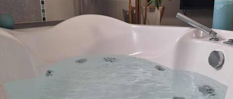 A bathtub filled with water, a bamboo plant, and a blue towel.