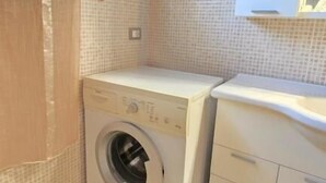 A compact laundry room with a washing machine, a dryer, and a small cabinet. - La Nocina (Santa Sofia)