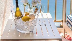 A table with a bottle, glasses, flowers, and ice cubes on a balcony with a view of the sea. - 180° ocean view, 20 m² terrace, beach right below the residence, private parking, Monaco (Roquebrune-Cap-Martin)