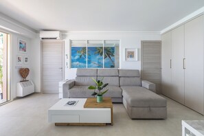 Ein modernes Wohnzimmer mit einem Ecksofa, einem Couchtisch, einer Topfpflanze und Kunstwerken an den Wänden.