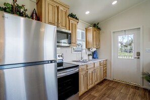 A modern kitchen with stainless steel appliances, wooden cabinets, and a window with a view.