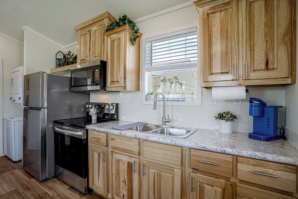A modern kitchen with wooden cabinets, stainless steel appliances, and a marble countertop. - Tiny Home Retreat Close to Lake Granbury (Granbury)