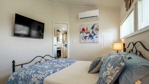 Una camera da letto con un letto, una televisione, un condizionatore d'aria e un quadro appeso al muro.