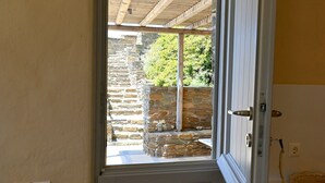 Puerta que da a un espacio al aire libre cubierto, con paredes de piedra y techo de madera.