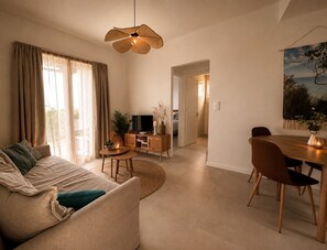 Ein modernes Wohnzimmer mit Sofa, Esstisch und Fernseher.