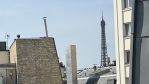 Un paisaje urbano con una torre destacada al fondo, presumiblemente la Torre Eiffel, y una variedad de edificios de distintos estilos arquitectónicos.
