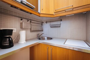 Una cocina moderna con armarios de madera, un lavamanos de acero inoxidable, una cafetera y un hervidor.
