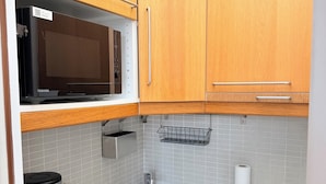 Una cocina compacta con microondas, cafetera y pileta.