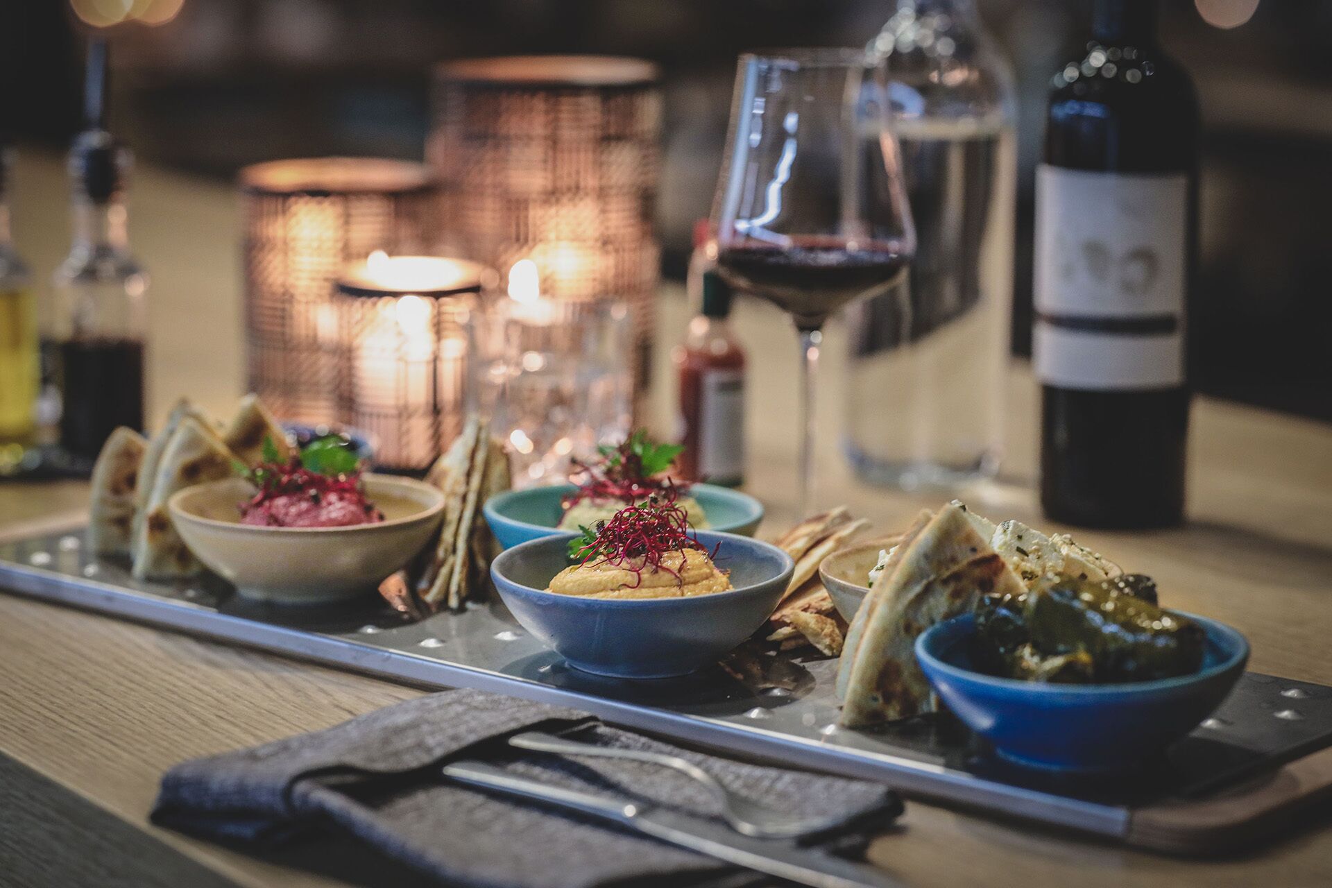 Una mesa de comedor con varios platos, copas de vino y velas.