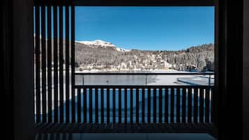 Vista da un balcone con ringhiera su un paesaggio innevato con un lago e edifici.