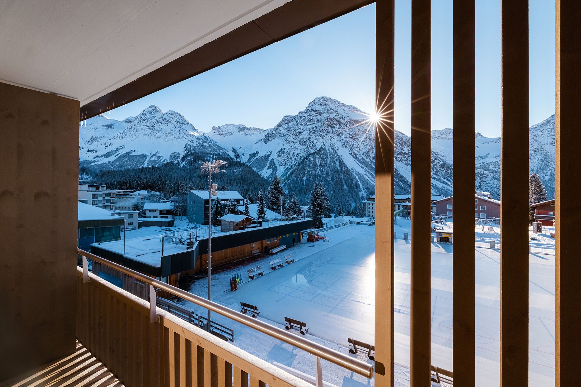 A view from a window overlooking a snowy mountain landscape with a ski resort.