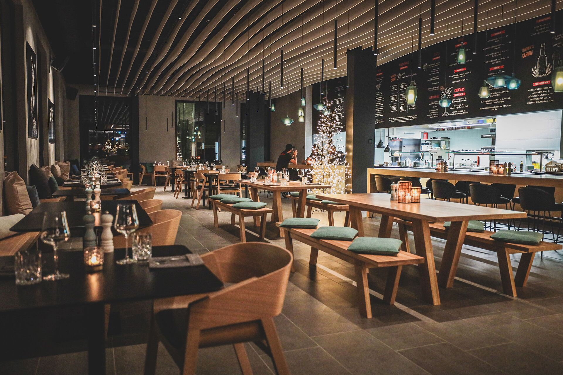 Un ristorante con tavoli e sedie in legno, un'area bar e una lavagna con il menu.