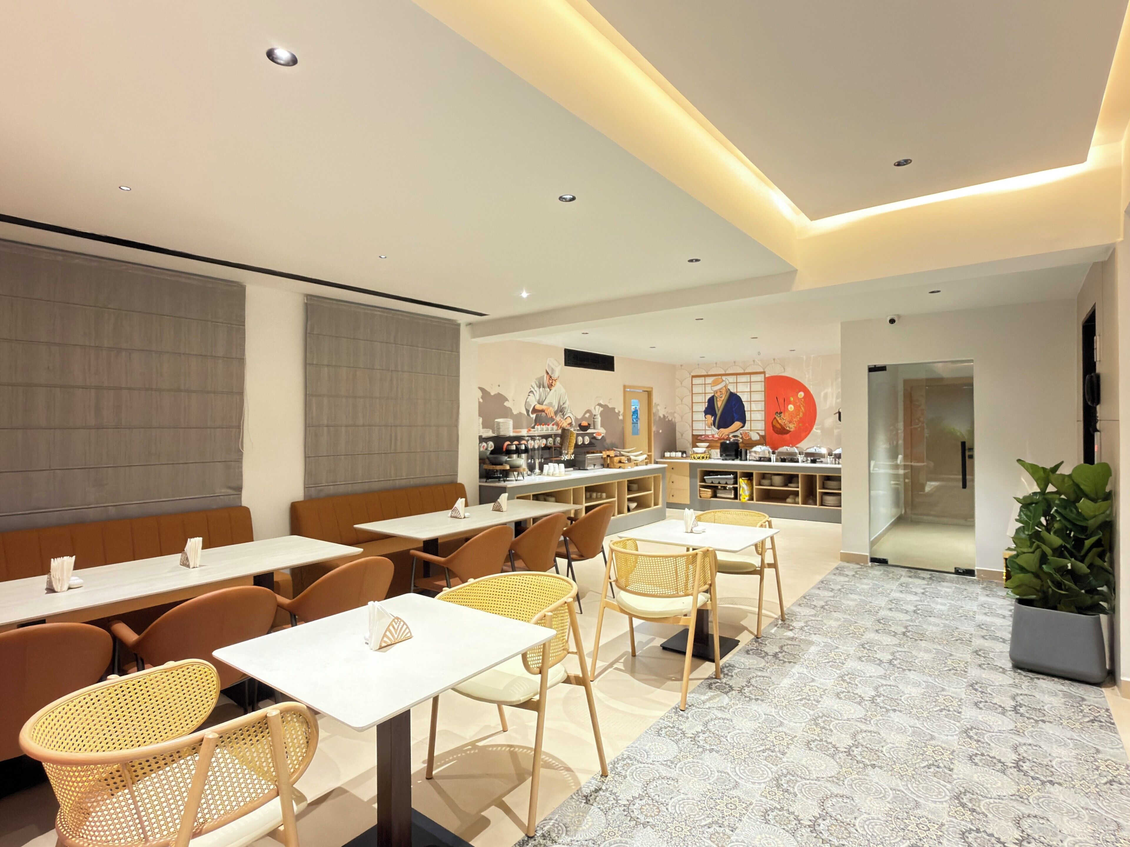A modern restaurant interior with a central kitchen, seating area, and a patterned floor.