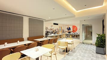 A modern restaurant interior with a central kitchen, seating area, and a patterned floor.