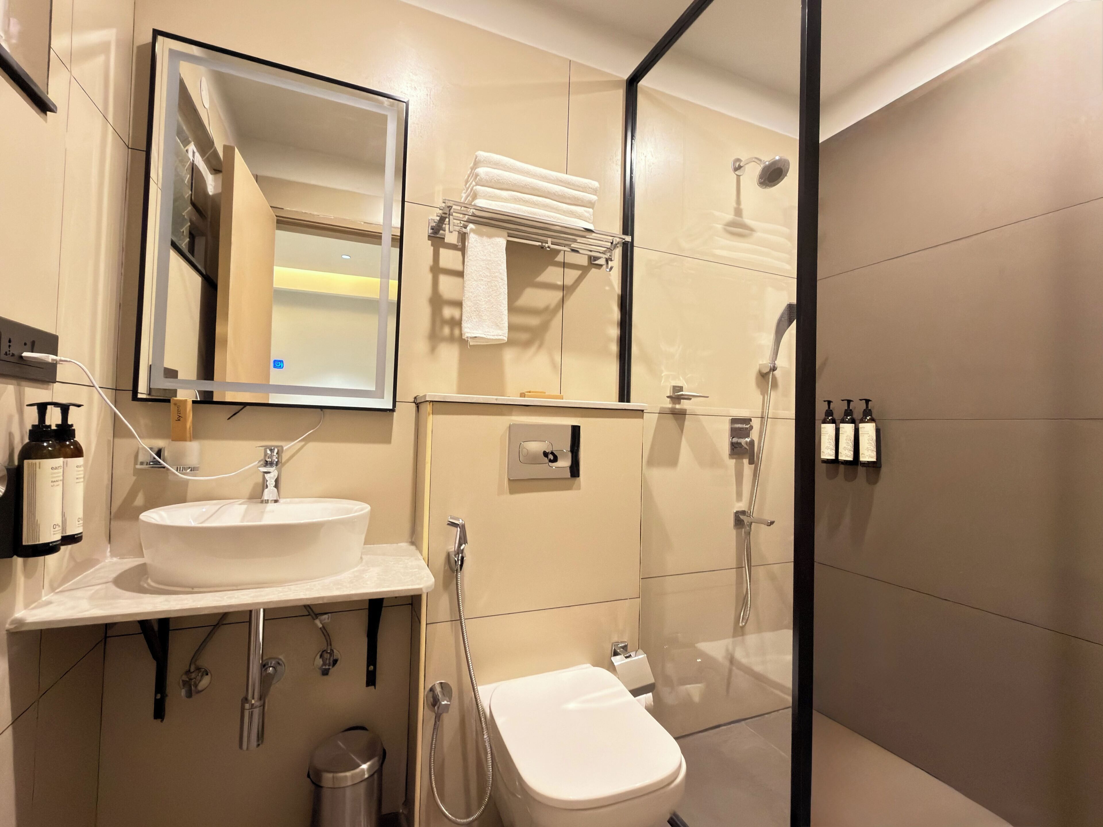 Un baño moderno con lavamanos, espejo, inodoro y ducha.