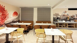 A restaurant interior with booths, tables, and a chef preparing food. - Hotel Kyzen - Shamshabad Airport (Hyderabad)