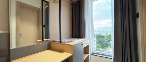 Un baño moderno con tocador de madera, espejo, toallero y ventana con cortinas.
