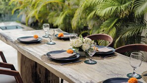 A long dining table set with plates, glasses, and a centerpiece of white flowers. - Calma Cliff Villas  (Ungasan)