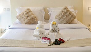 A hotel room with a neatly made bed, two decorative towels, a card, and a rose. - Calma Cliff Villas  (Ungasan)