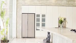 A modern kitchen with a built-in refrigerator, a sink, and a countertop with a vase of flowers. - Calma Cliff Villas  (Ungasan)