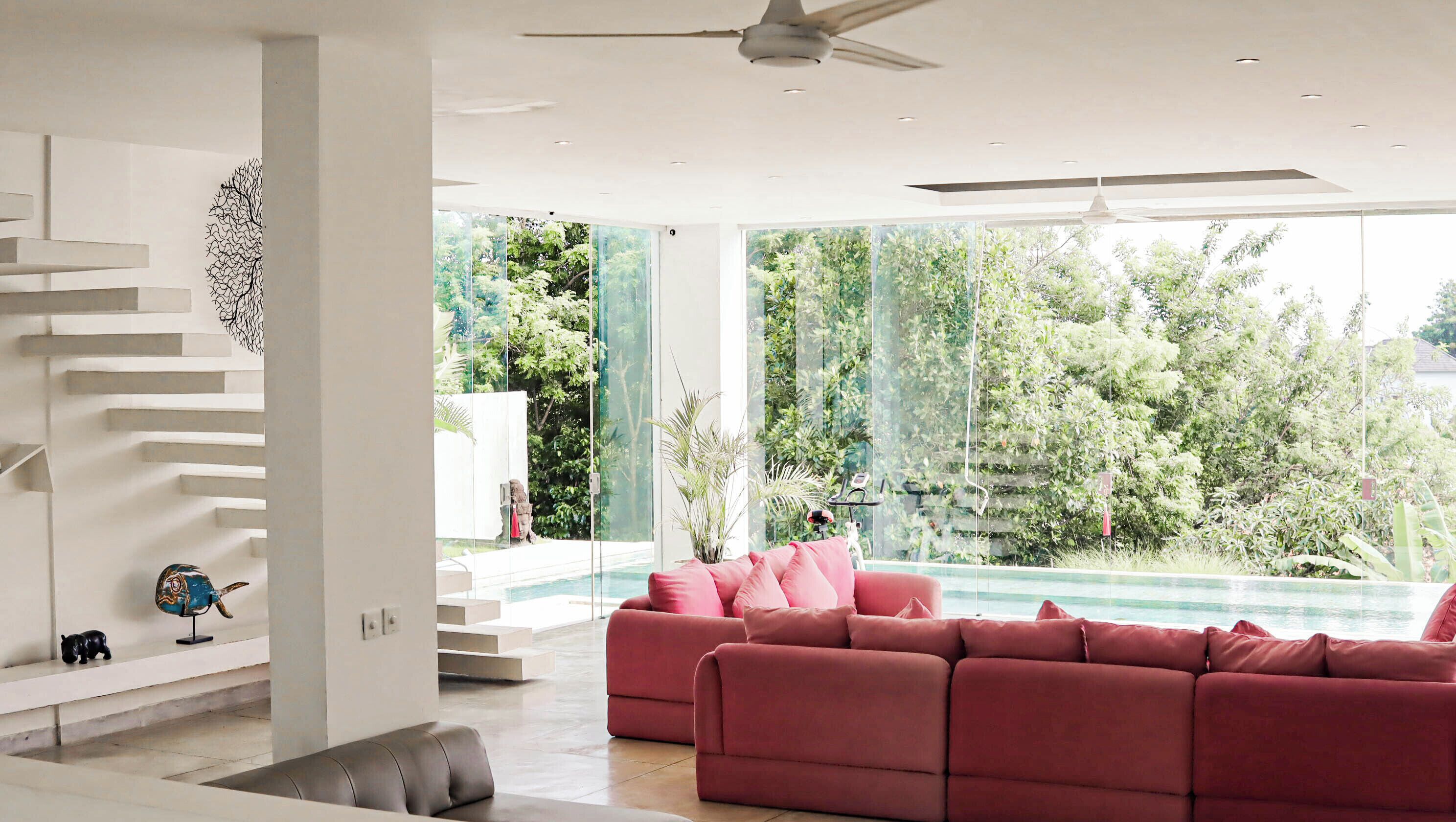 Un salon moderne avec un canapé rouge, un escalier et une vue sur une piscine.