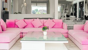 Um sofá rosa com uma mesa de centro de vidro em uma sala de estar moderna.