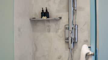 A bathroom with a shower, a towel rack, and a shelf with two bottles.