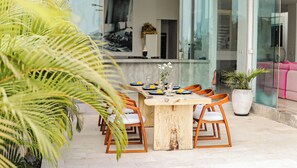 A dining area with a wooden table and chairs, a vase with flowers, and a potted plant. - Calma Cliff Villas  (Ungasan)